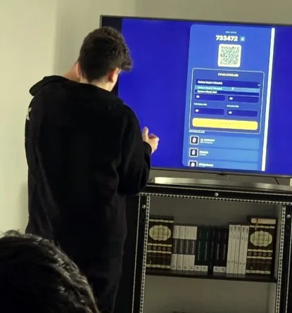 طالب أمام شاشة تعرض تطبيق اللعبة ورمز QR.